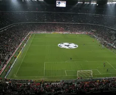 Een voetbalstadion met een grote afbeeldingsscherm en een logo in het midden van het veld.