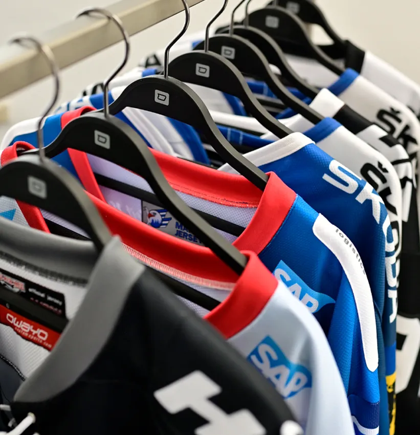 Een rij gekleurde, op maat gemaakte sportkleding van owayo hangt aan zwarte kledinghangers aan een kledingrek.