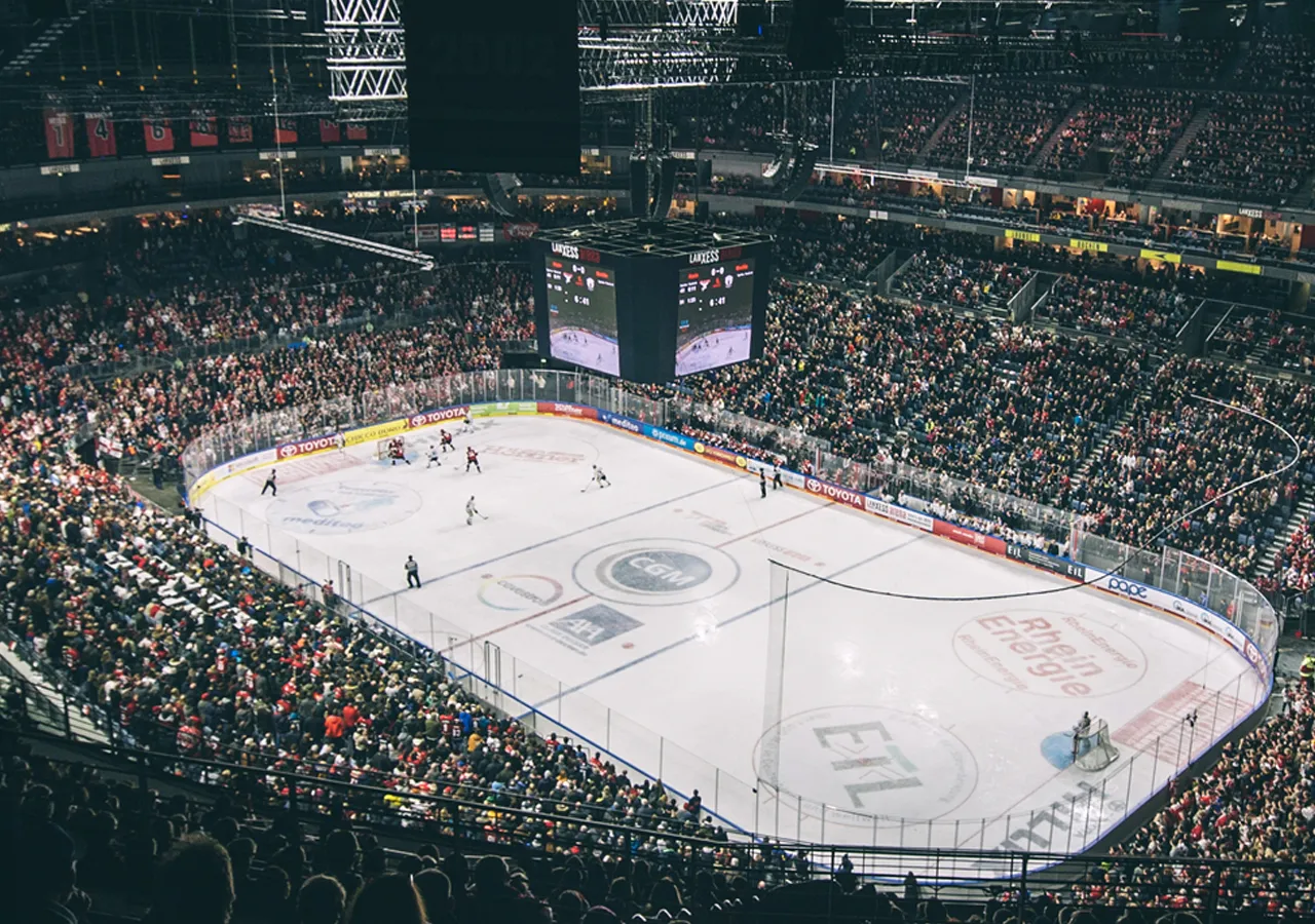 Een breed uitzicht op een ijsarena tijdens een hockeywedstrijd met een grote menigte.