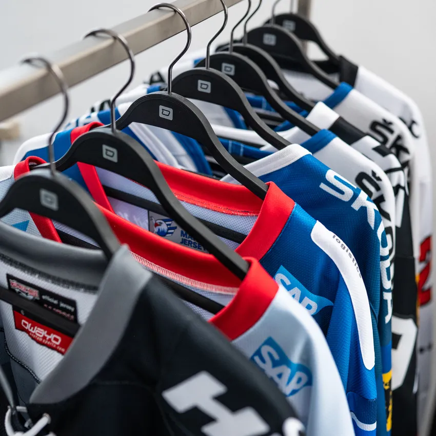 Een rij van verschillende gekleurde sportshirts die aan een hanger hangen.