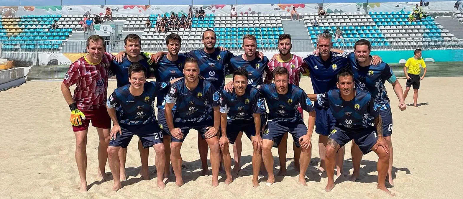 Een voetbalteam poseert op een zandveld in aangepaste sportkleding gemaakt door owayo.