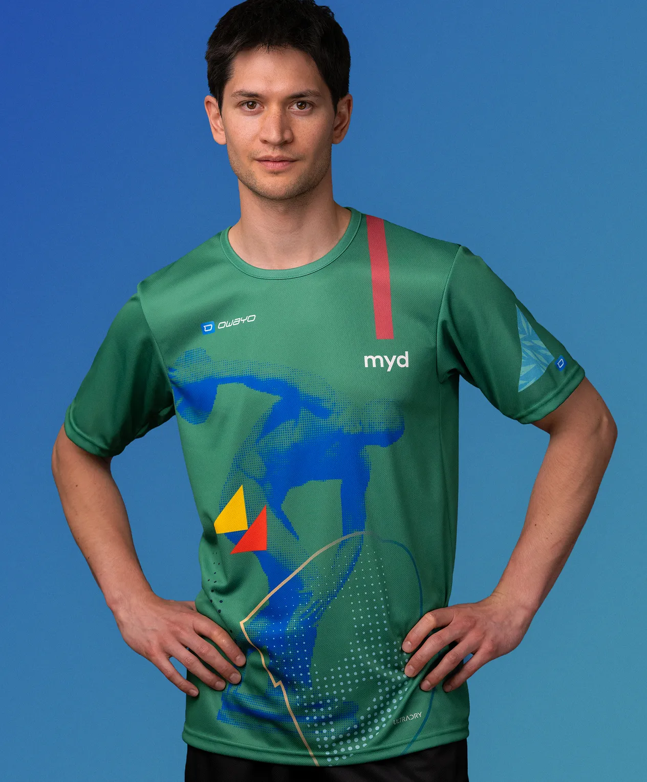 Een man in een groen, op maat gemaakt sportshirt van owayo met een blauw, geel en rood grafisch ontwerp en de tekst 'myd' op de borst.