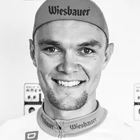 Een man in een fietspak met het logo 'Wiesbauer' op de pet en het shirt.