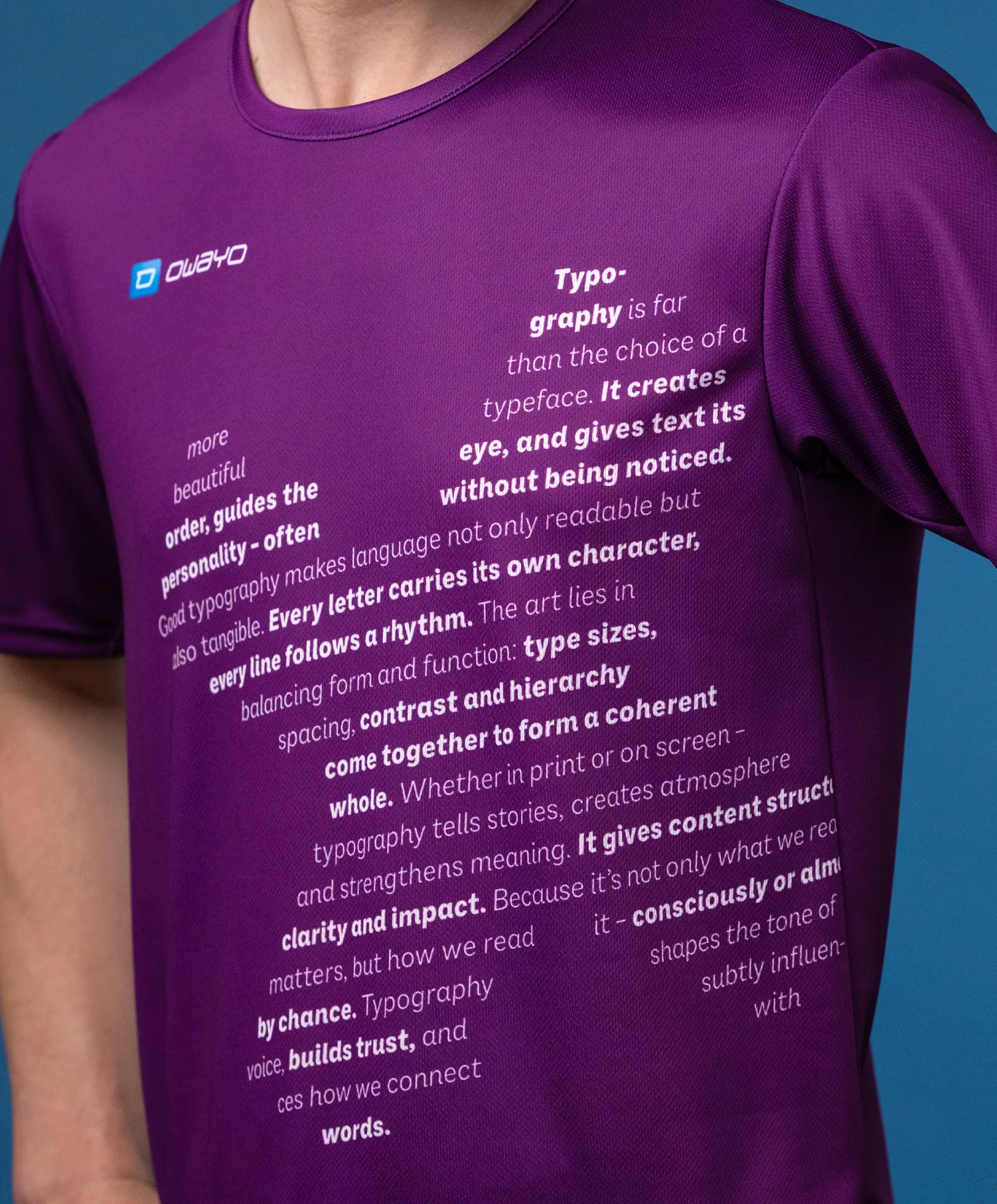 Een close-up van een paarse sportshirt met verschillende typografische teksten aan de voorkant, gedragen door een model.
