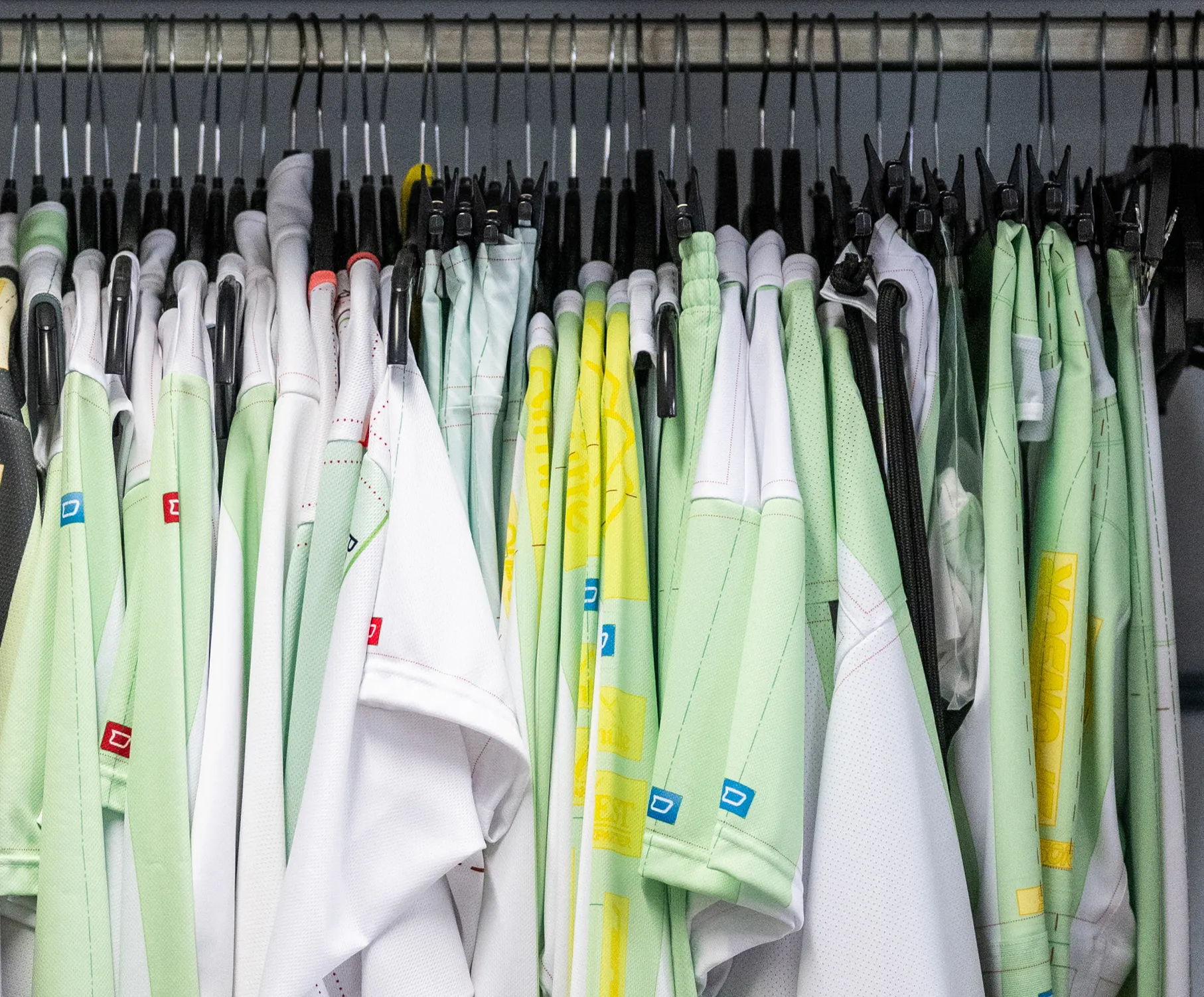 Een selectie van op maat gemaakte sportkleding in verschillende kleuren, aan kledinghangers hangend.