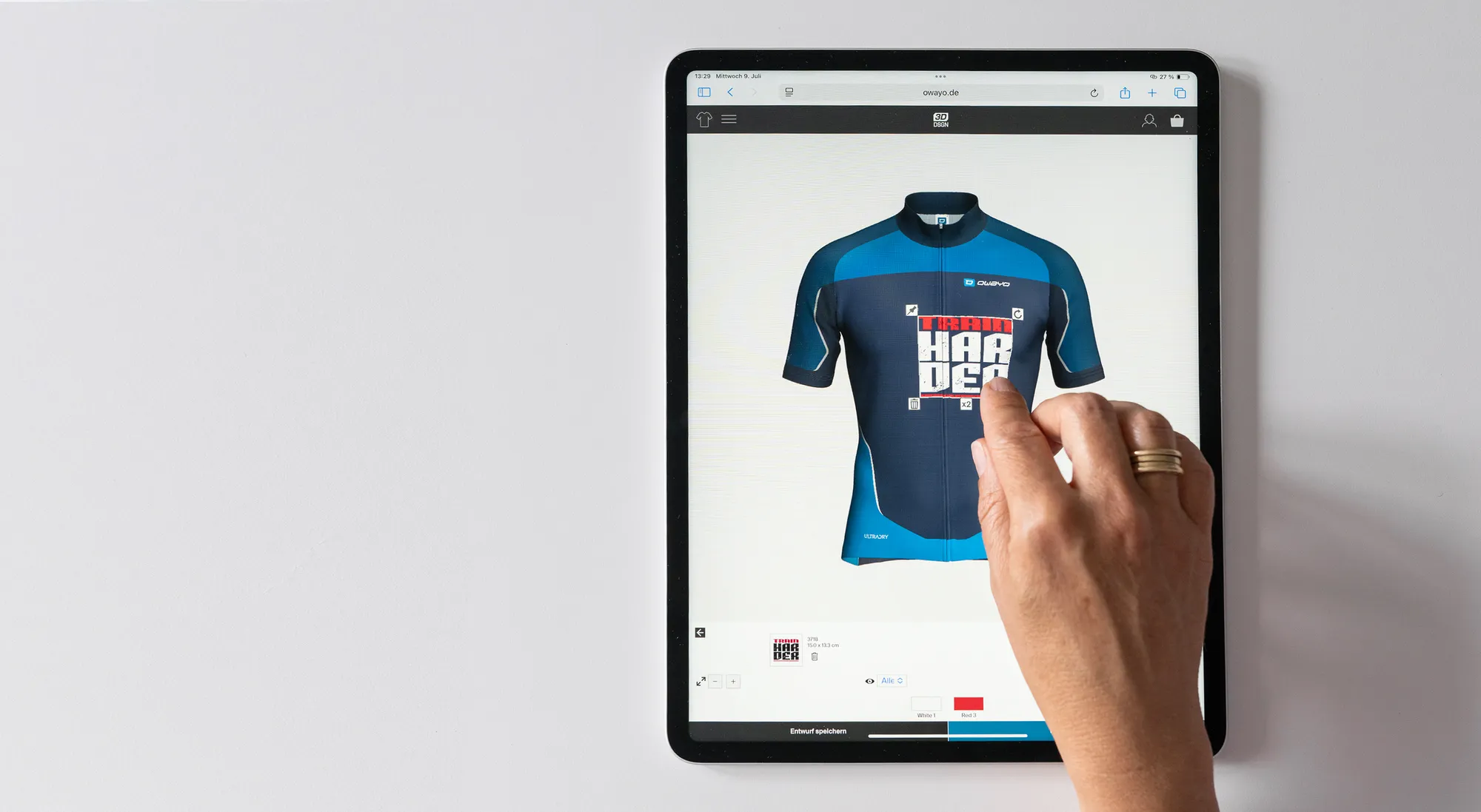 Een hand interageert met een tablet waarop een aangepaste fietsjersey-ontwerpopdracht van owayo wordt weergegeven, waarbij een blauw jersey met een rood en wit ontwerp wordt bewerkt.