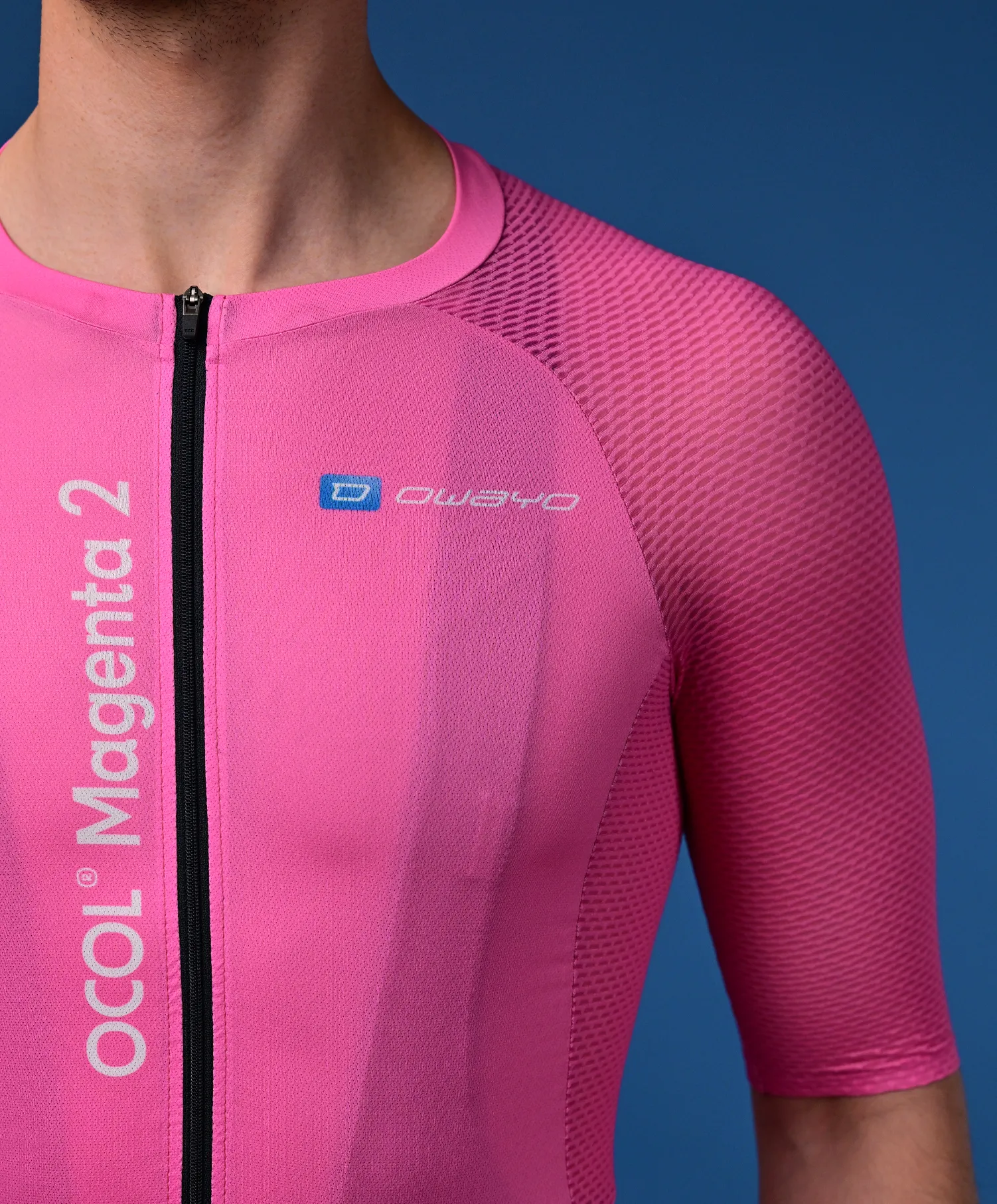 Een man draagt een roze, korte mouwen fietsjersey met een zwarte rits en het 'owayo' logo op de borst. Verticaal aan de linkerkant staat 'OCOL Magenta 2'.