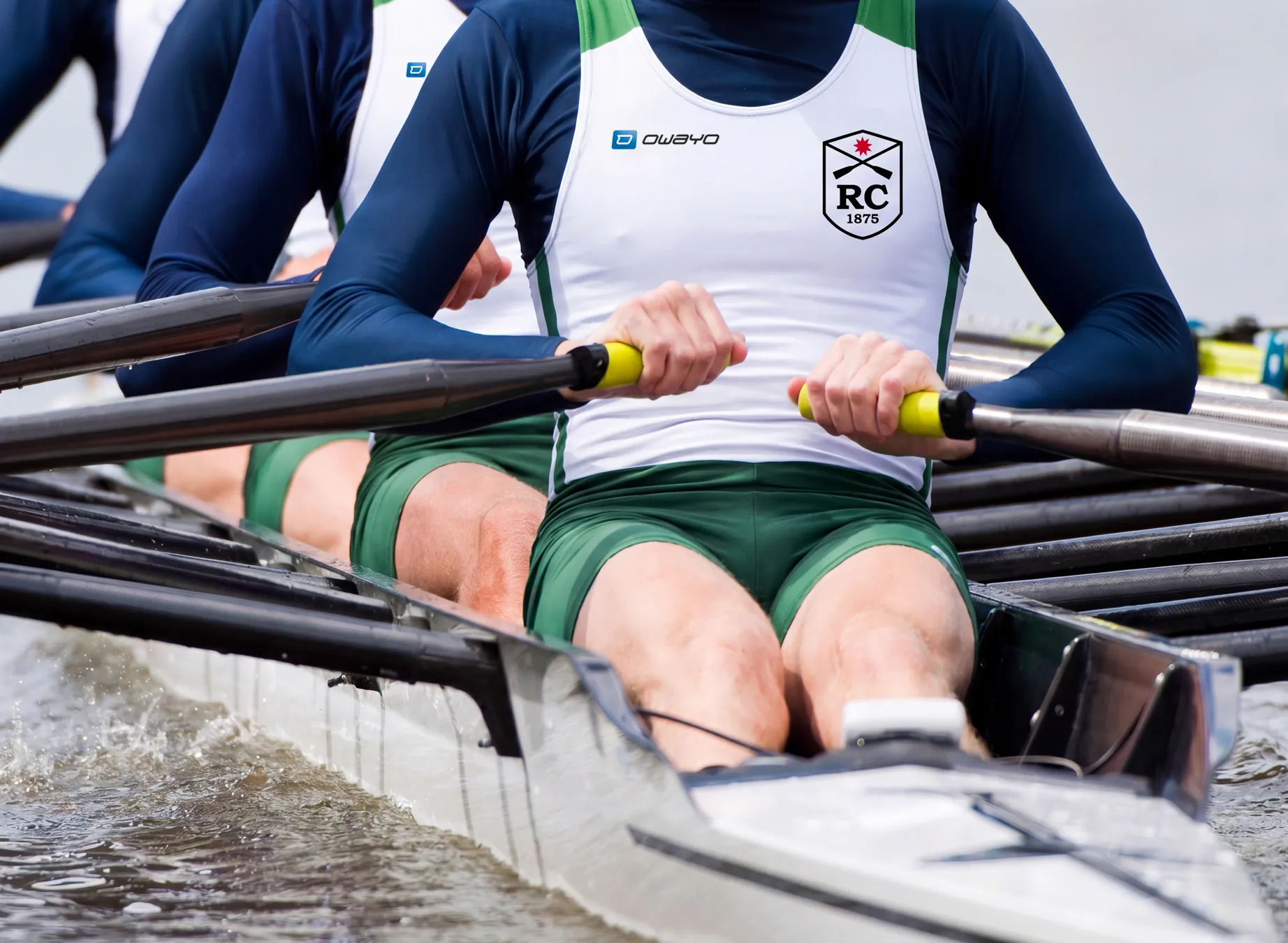 Een groep roeiers in op maat gemaakte sportkleding, die actief in een boot roeien.